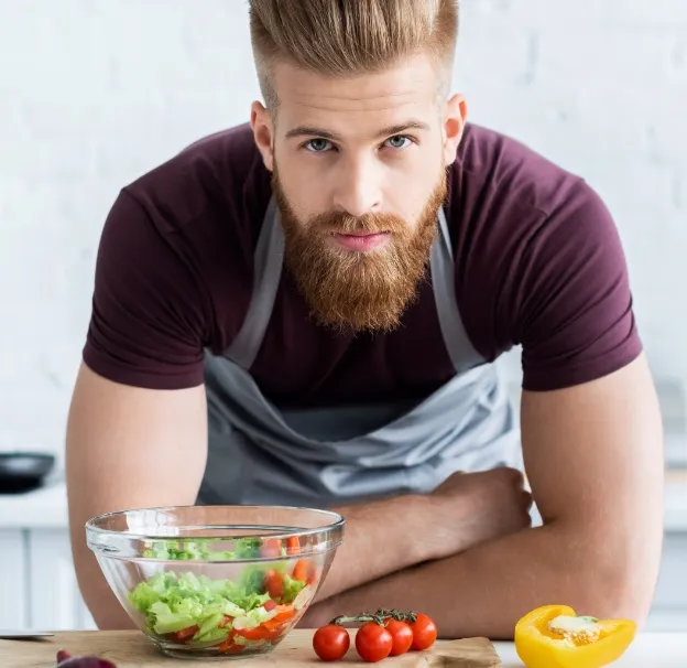 handsome bearded man in apron cooking vegetable sa utc